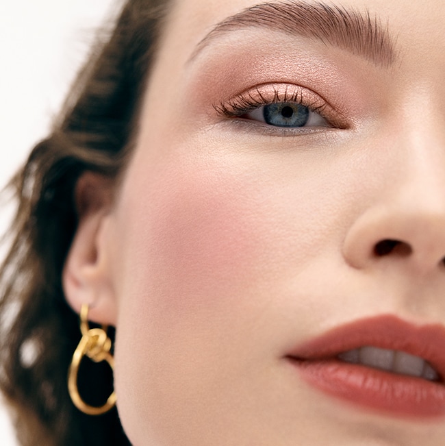 Model applying Skin Long-Wear Weightless Foundation to skin with a foundation brush